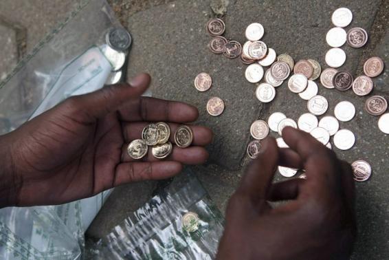 A Zimbabwean street vendor sorts new coins in front of a bank in Harare, December 18, 2014. Reserve Bank of Zimbabwe governor John Mangudya introduced the new "bond coins" in December 2014. REUTERS/Philimon Bulawayo